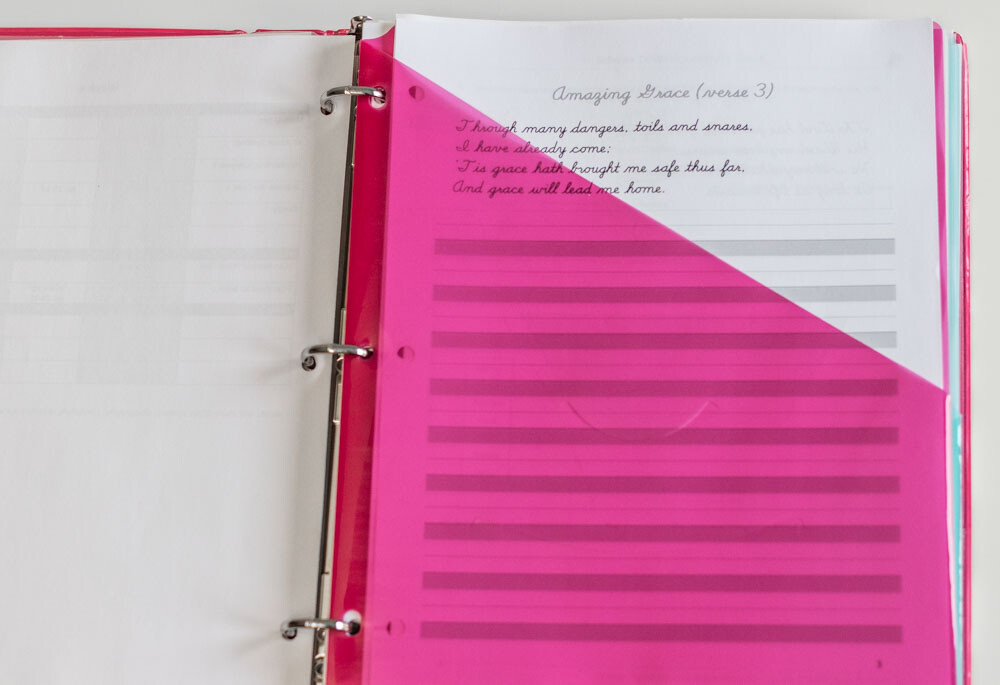 Teaching binder open to a pink slash pocket filled with the current week's assignments