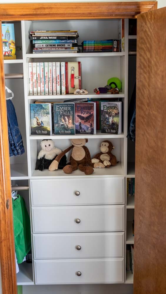 The boys' closet after adding a complete system from EasyClosets featuring drawers, shelves, and three hanging rods.