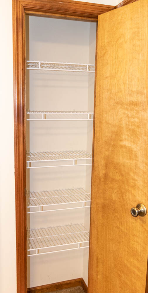 Full view of empty linen closet with wire shelving before renovation with EasyClosets.